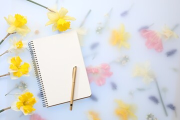 Guest list. Notebook, pen and daffodils on spring floral background, flat lay. Space for text