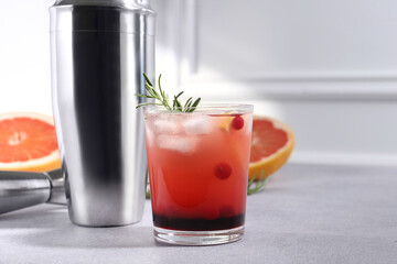 Delicious cocktail, grapefruit and bartender equipment on light grey table, space for text