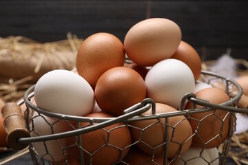 Fresh chicken eggs in metal basket on table, closeup