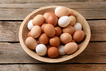 Chicken eggs in bowl on wooden table