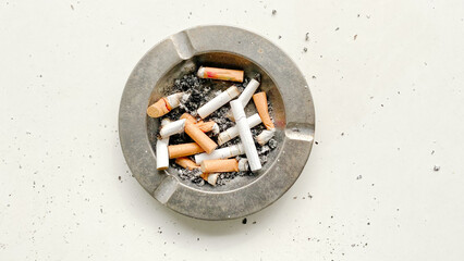 Ashtray full of cigarettes butts close-up on white background - obrazy, fototapety, plakaty