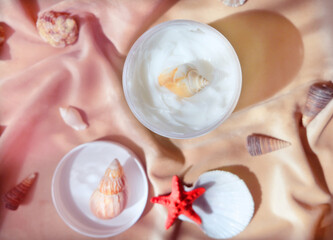 White  jar with skincare product. Summer decorations  with  seashell around cosmetology bottle.  Wellness, mockup and beauty concept.