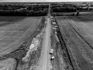 High angle view of a road construction project cutting through an agricultural district of farm...
