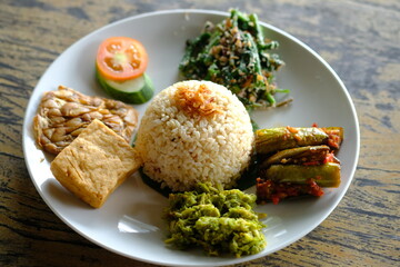 Nasi Campur Bali or nasi rames. brown rice with sautéed vegetable, fried tempeh and tofu. Balado...