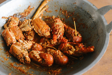 Cooked lobster with red spicy pepper seasoning served in cooking wok