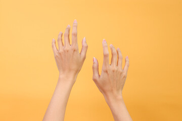 Woman hands in the air over yellow background