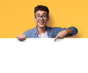 Excited happy young man wear glasses, braces stand behind, peep empty banner mockup sign board signboard, advertise show point sale slogan text place, isolated yellow background. Dental care ad