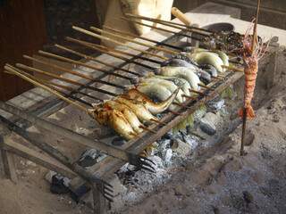 Cooking Japanese salt-grilled ayu sweetfish and shrimp skewers on street grill coals, Kusatsu, Japan