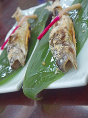 Japanese shioyaki aji salt-Grilled ayu sweetfish on bamboo leaves decorated with hajikami pickled...