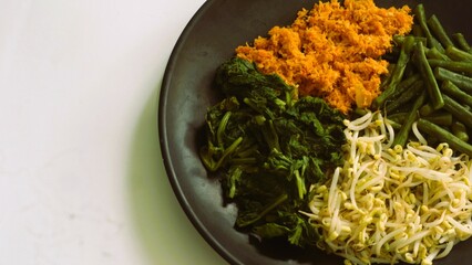 Urap, Indonesia traditional food served on plate with white background. Salad dish consist of...