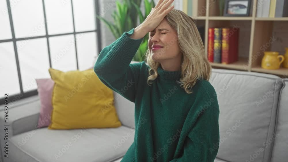 Wall mural angry young blonde woman sitting on home sofa, symbolically showing rejection and discontent with se