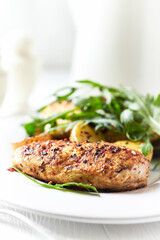 Grilled Chicken Breast with oven baked potatoes and fresh rocket. Bright background. Close up.
