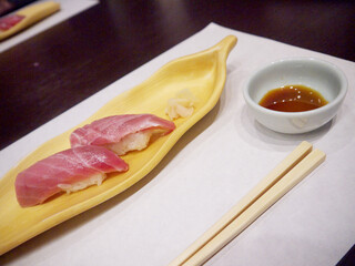 Leaf shaped wooden Plate with two pieces of tuna nigiri sushi with soy sauce and ginger
