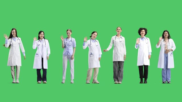 A group of doctors, in full height, on a green background, waving their hands
