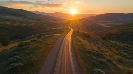 Fototapeten The sun sets over a tranquil mountain pass its last rays casting a warm glow on the empty road ahead. . AI generation. © Justlight