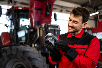 Professional mechanic servicing tractor gears transmission inside workshop. - obrazy, fototapety, plakaty