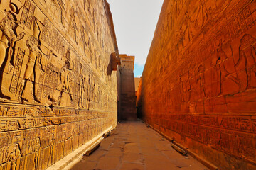 Rich yellow sandstone walls decorated with the story of Horus and Ptolemaic kings in the Temple of...