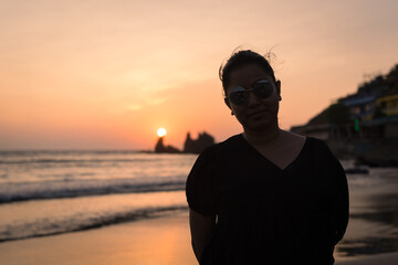 Beautiful young Indian woman Enjoying the beautiful sunset at Goa Beach in India. Delightful girl...