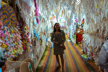 Happy young Indian woman standing inside a dreamcatcher shop in Arpora night Market in India