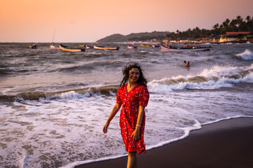 Happy beautiful young Indian woman smiling & relaxing at the Goa beach. Delightful girl enjoying...