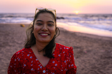 Happy beautiful young Indian woman smiling & relaxing at the Goa beach. Delightful girl enjoying...