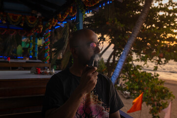 Indian man smoking a pipe and relaxing on the Beach in Goa, India
