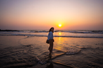 Happy carefree Indian woman  enjoying beautiful sunset on the Goa beach in India
