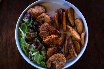 Delicious and crispy prawns with potato wedges and salad served in a plate. Authentic deep fried tiger prawn recipe from Goa, India.
