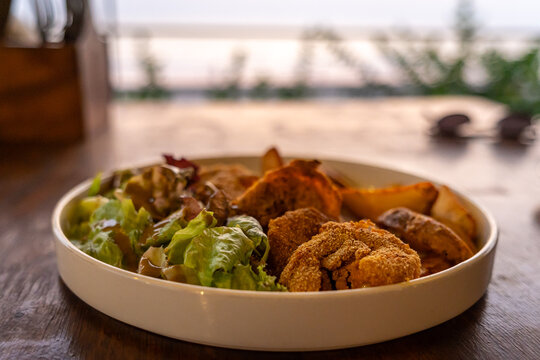 Delicious and crispy prawns with potato wedges and salad served in a plate. Authentic deep fried tiger prawn recipe from Goa, India.
