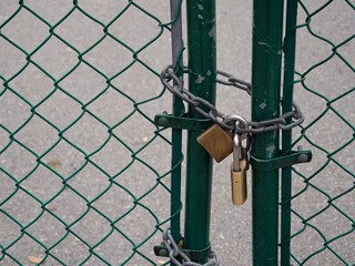 Close up of padlocks keeping the green park gate shut closed