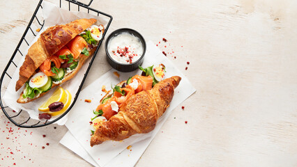 Salted healthy breakfast on light background. Fresh salmon croissant with cream cheese, cucumber,...