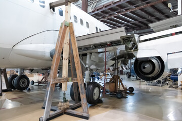 White passenger jetliner in the aviation hangar. Jet plane under maintenance. Checking mechanical systems for flight operations