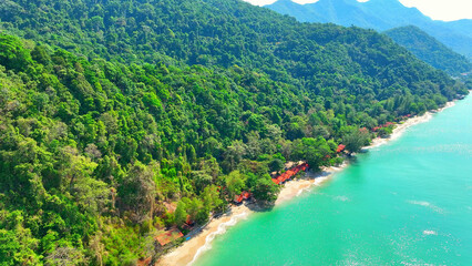Pristine beaches meet crystal-clear waters, with resorts nestled along the coastline. Lush mountains and a blue sky complete the breathtaking panorama. Mu Ko Chang National Park, Thailand.
