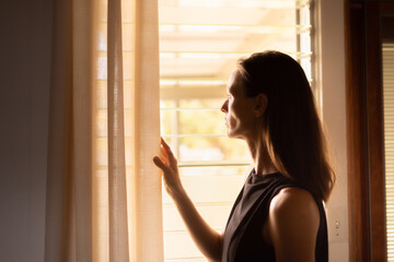 woman looking through window thinking pondering  - obrazy, fototapety, plakaty