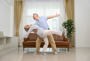 cheerful asian senior couple having fun dancing in the living room,family...