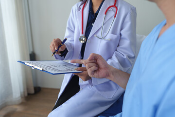 Physiotherapist giving advice and encouragement to male patient doing physiotherapy lying on...