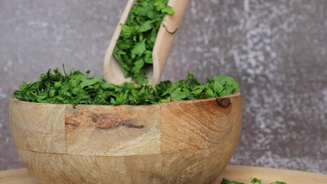 Dry parsley spice with wooden spoon in wooden bowl. Homegrown herbs and spices for cooking. Fresh dried aromatic natural food ingredients. 