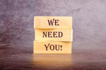 We Need You Message Concept written on wooden blocks on a dark background