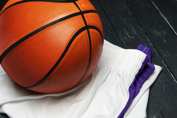 Vibrant Orange Basketball Resting on a Dark Wooden Floor With White and Purple uniform