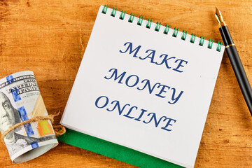 Business concept. MAKE MONEY ONLINE lettering written on a notepad near money and a fountain pen on...