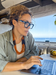 Curly woman looks at her laptop monitor which she uses to communicate with friends and family...