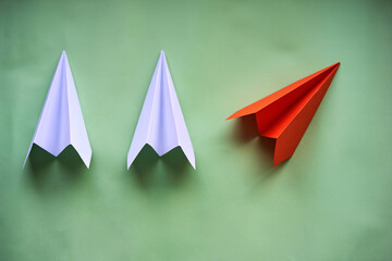 Paper airplanes in a green background. One stands out from the rest. Concept of creativity and...