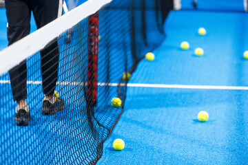 Twoo balls next to the net of a blue paddle tennis court. Sport healthy concept.