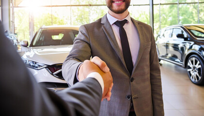 Car buyer shaking hands with salesman at auto dealership, in the background blurry luxury cars with light entering from the display window. Auto business and car sale concept. Generative Ai.