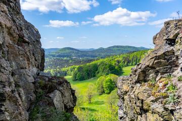 A scenic view of the Lusatian Mountains with rugged cliffs in the foreground and dense green...