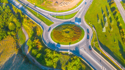 Aerial perspective of a busy roundabout with multiple exits, surrounded by lush green trees and...