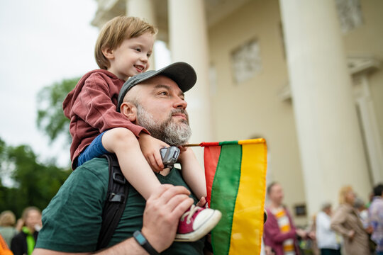 Cute little boy and his father holding tricolor Lithuanian flag celebrating Lithuanian Statehood Day in Vilnius