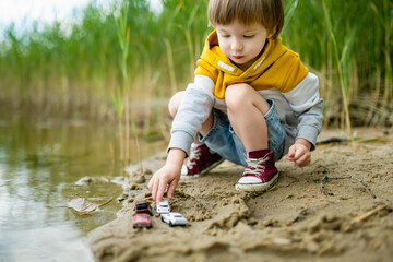 Cute little boy playing by a lake or river on hot summer day. Adorable child having fun outdoors during summer vacations.