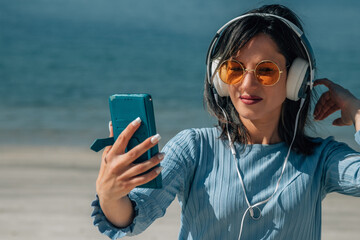 woman with headphones and mobile phone enjoying on the beach