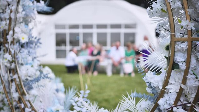 Wedding arch flowers in the background of the guests waiting for the wedding registration in nature.